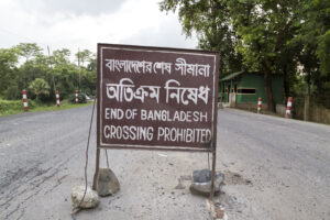 Kotwali gate, 1235-1315. Land border of Bangladesh and India. Brown sign in the middle of the road declaring the end of Bangladesh, crossing prohibited.