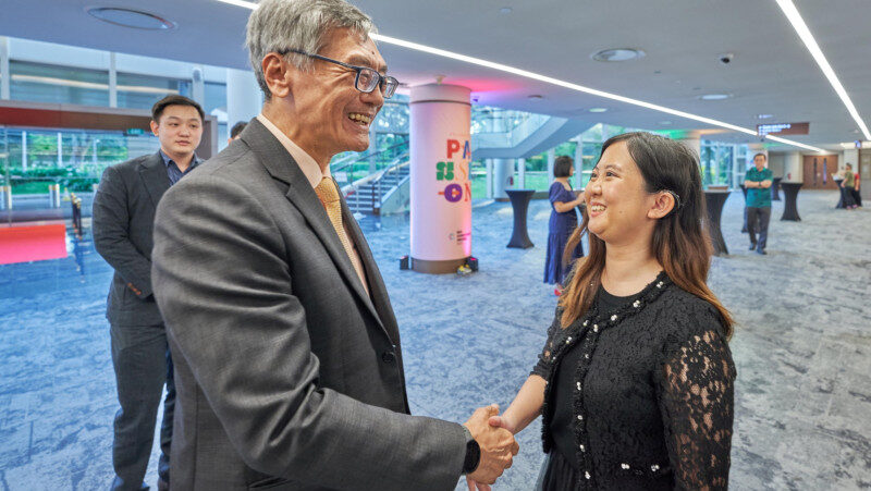Nicolette, recipient of the Leadership Distinction award at the NUS Achievement Awards 2024, meeting NUS President Professor Tan Eng Chye at the awards ceremony.
